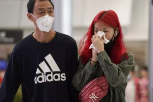 1月23日（木）、香港の高速鉄道の駅で鼻をかむ女性。AP - Kin Cheung