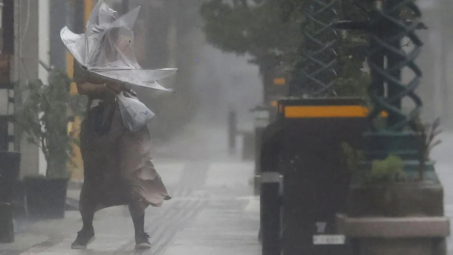 強力な台風ナンマドールが南日本を襲ったため、2022年9月18日に南日本の宮崎の強風と雨を通り抜ける女性。© AP - 協同