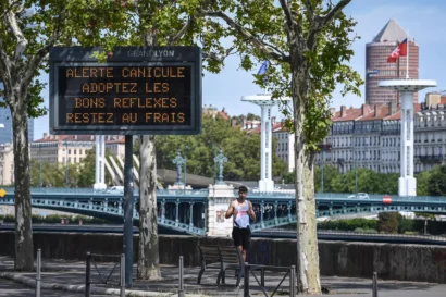 ランナーは、2023年8月18日にリヨンで熱波の警告の標識を通り過ぎてジョギングします。© OLIVIER CHASSIGNOLE / AFP